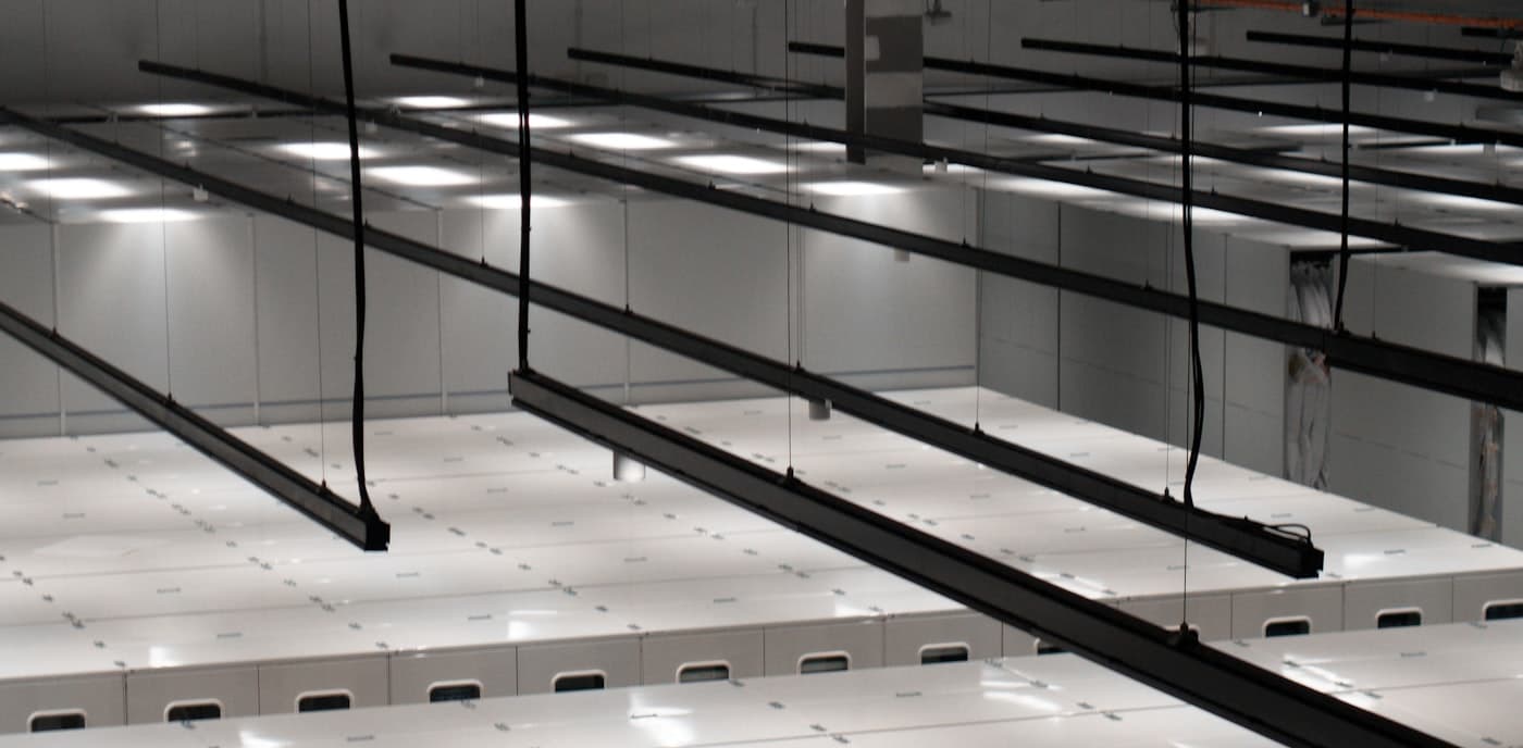 A bright, empty data-hall aisle lined with white server cabinets.
